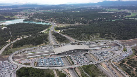 Luftaufnahme-Des-TGV-Bahnhofs-Aix-en-Provence,-Bewölkter-Tag,-See-Im-Hintergrund,-Park